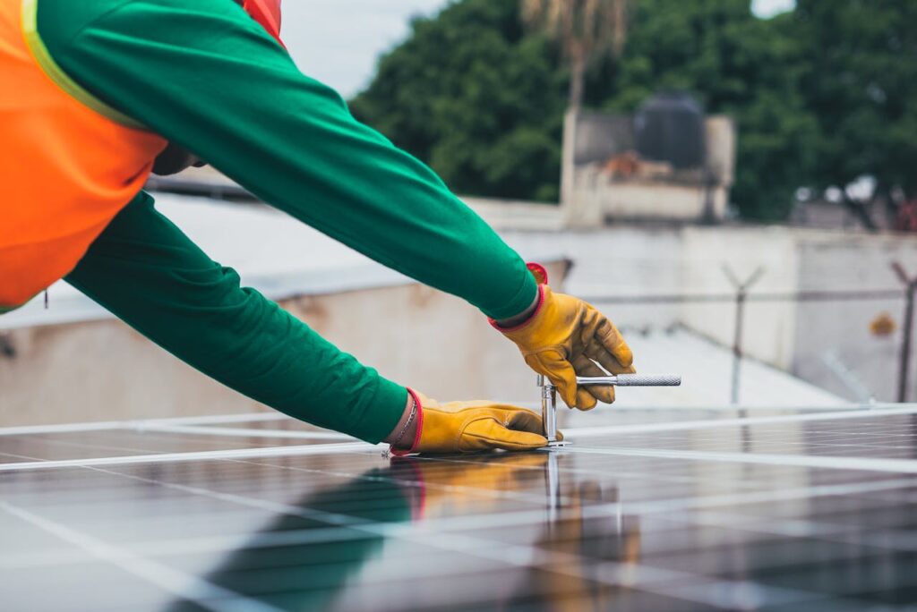 A solar technician working on the installation of solar panels on a rooftop with focus on tools and safety gear.